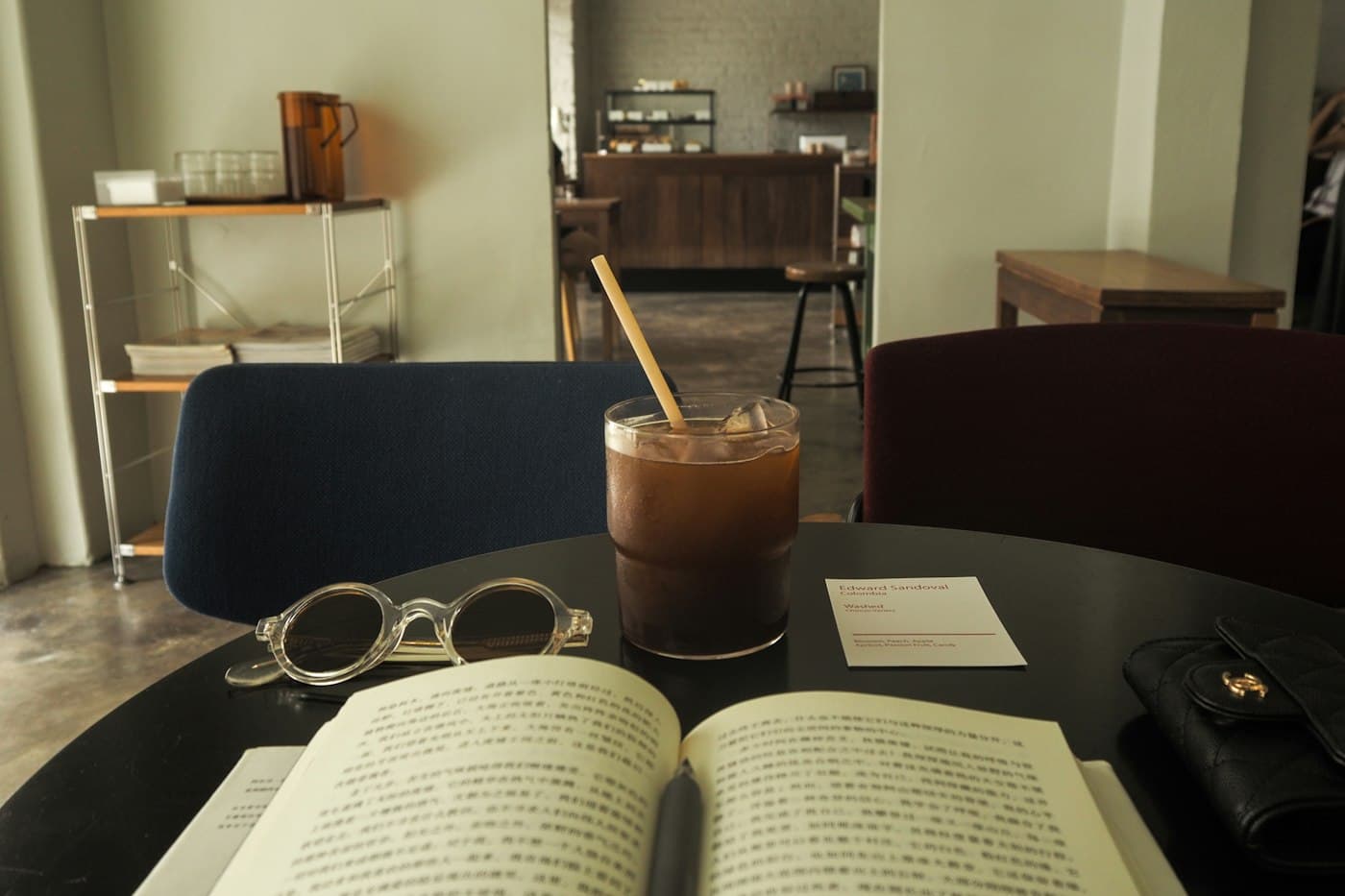 An open book and an iced coffee on a café table