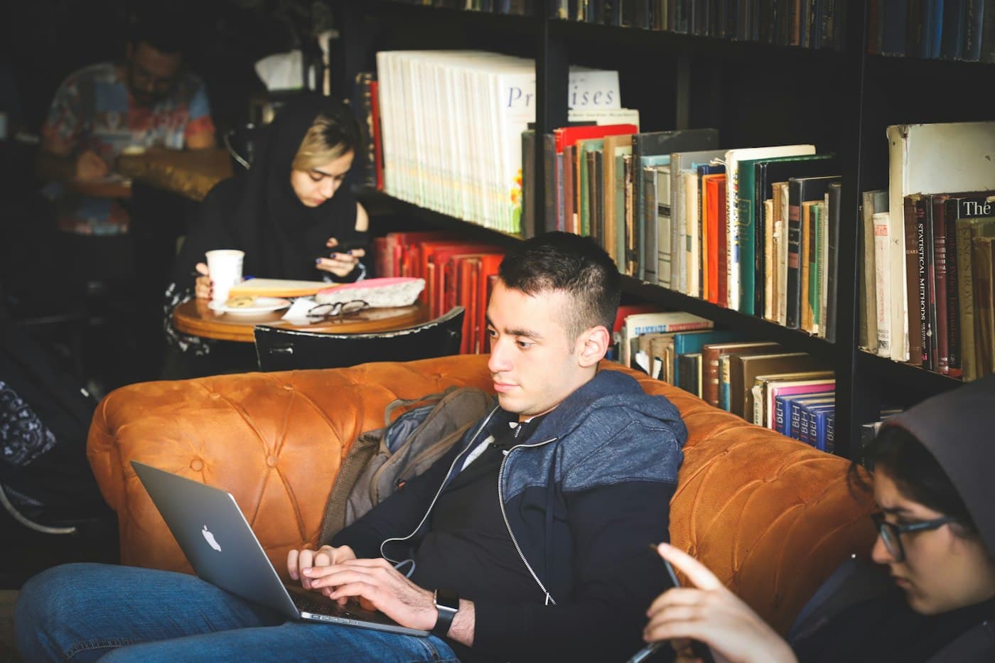 Students studying in armchairs next to library bookshelves